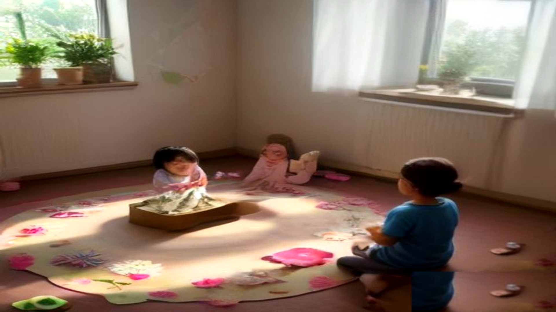 Ronda en alfombra de sala de jardín: docente con caja de cartón decorada con flores de papel y niños levantando la mano, témperas y sol en la ventana.